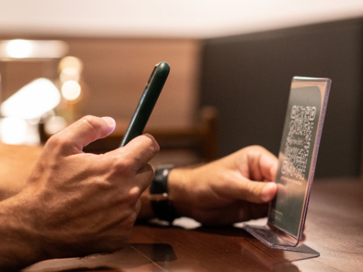 Misafir masadaki QR kodu telefonuyla okutuyor